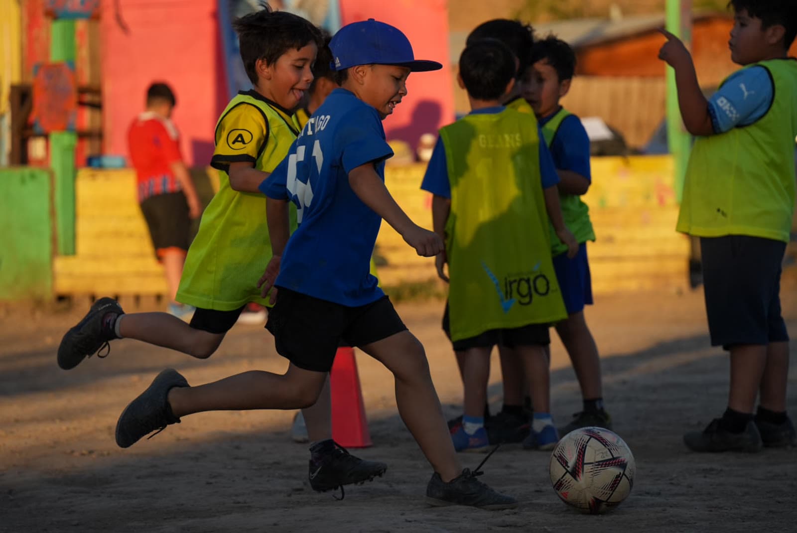 Niños corriendo y celebrando durante un entrenamiento en la cancha del barrio